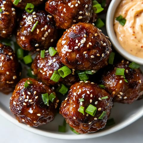 A plate of meatballs with a spicy mayo dip.