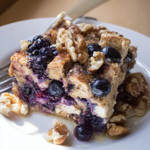 Delicious Protein Blueberry French Toast Bake, fresh blueberries nestled, sweet maple syrup drizzle.
