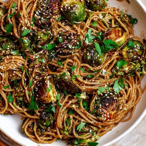 Golden, crispy Maple-Soy Roasted Brussels Sprouts Pasta topped with sesame seeds and fresh parsley.