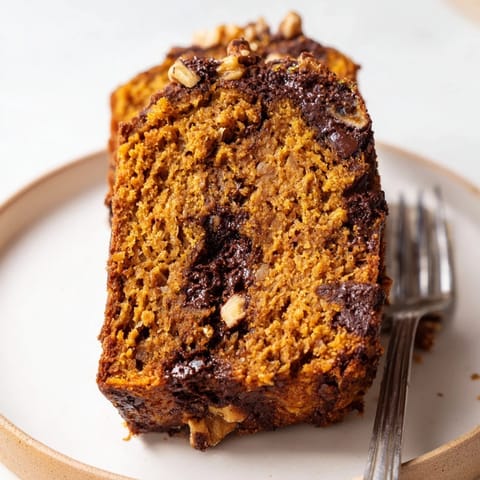 Slice of golden Protein Pumpkin Banana Loaf fresh out of the oven, showcasing rich flavors.  