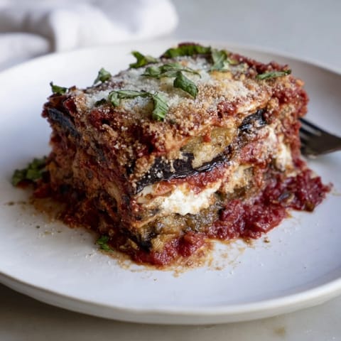 Golden brown Eggplant Parmesan Lasagna, topped with crispy Parmesan and fresh basil.  