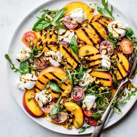 Sweet grilled peaches and creamy burrata create a delightful summer salad experience.  