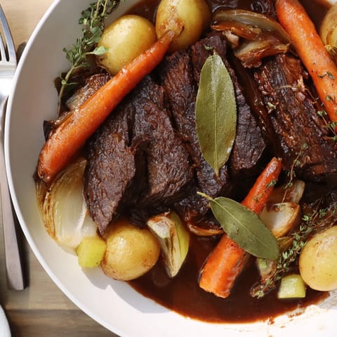 Hearty beer-braised brisket surrounded by vibrant root vegetables on a cozy table.  