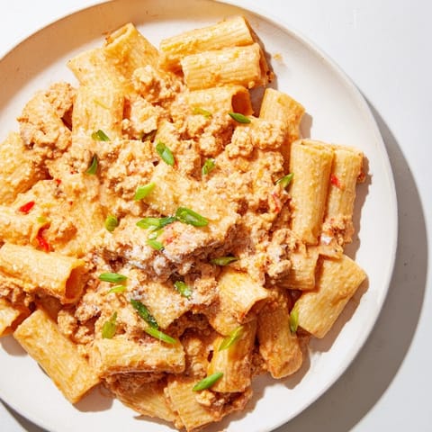 A close-up shot of the savory Chaos Cooking Kimchi Ragu Pasta, garnished with fresh green scallions.
