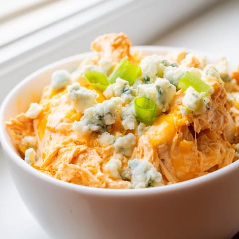 Golden, bubbly Buffalo Chicken Dip fresh from the oven, served with crisp celery sticks and carrots for a classic game-day snack.  