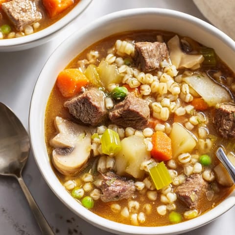 Hearty Beef and Barley Soup in a rustic bowl, garnished with fresh parsley and served with crusty bread.