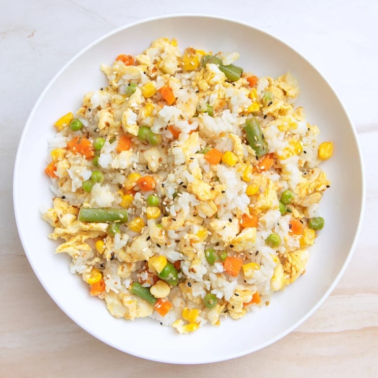 Steaming plate of Frozen Veggie Fried Rice, mixed with vegetables and savory soy sauce.