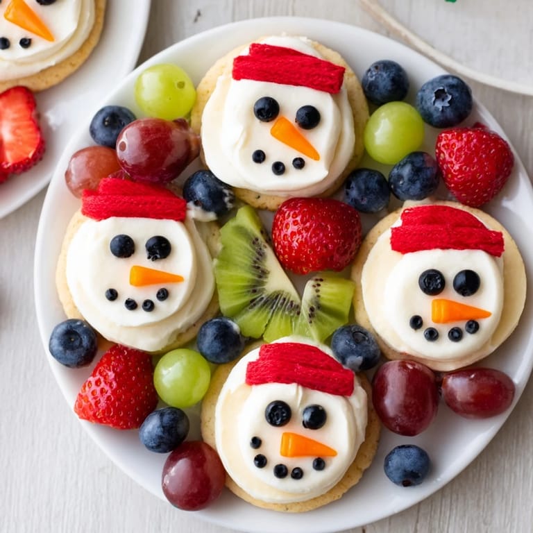 Festive Melting Snowman Fruit Pizza with smiling marshmallow snowmen and colorful fruit toppings.