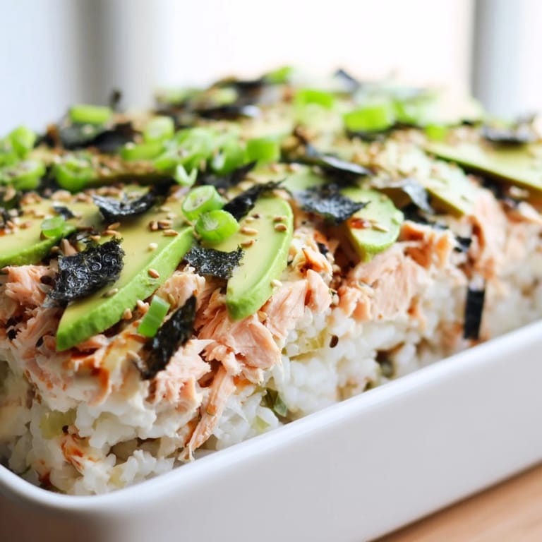 A warm, comforting Sushi Bake Casserole, with visible layers of rice, flaked salmon, and creamy avocado.