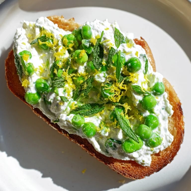 Whipped ricotta and sweet peas topping toasted sourdough: a beautiful pea & mint toast.