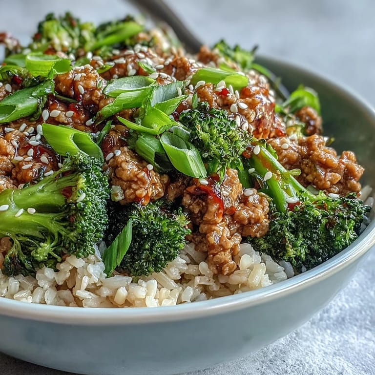 A close-up of a Sweet and Spicy Turkey Broccoli Bowl, featuring saucy turkey, bright green broccoli, brown rice, and scallions for a quick dinner.
