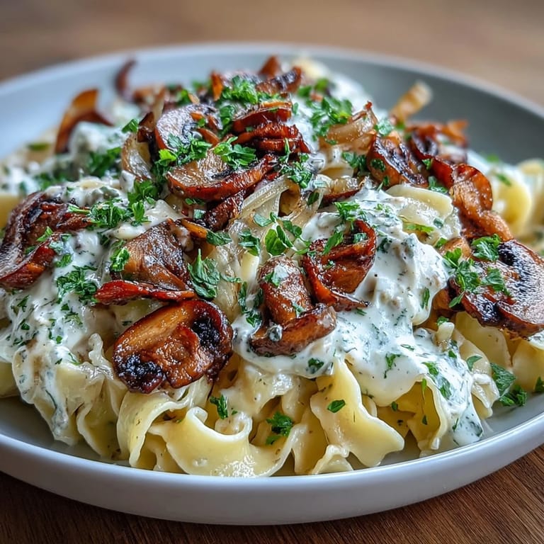 Vegetarian stroganoff featuring sautéed onions and mushrooms in a rich, creamy sauce over wide egg noodles.  
