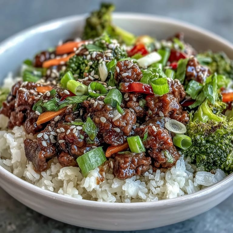 Colorful beef and vegetable bowl featuring tender beef, crisp broccoli, bell peppers, and carrots, served over steaming rice for a satisfying meal.