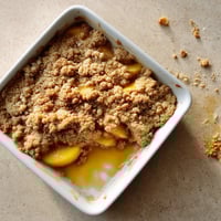 A white bowl of food with a peach on top.