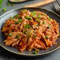 A plate of chicken with green onions.