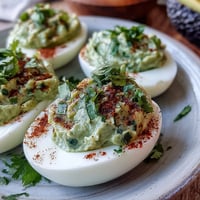 Green avocado deviled eggs with fresh herbs, a vibrant spring appetizer perfect for parties and gatherings.