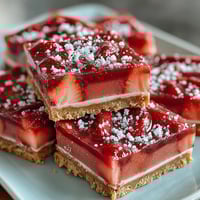Bright pink strawberry lemonade bars with tangy citrus filling and buttery shortbread crust, dusted with powdered sugar for a refreshing spring dessert.