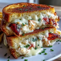 Golden-brown Lobster Grilled Cheese with gooey melted cheese spilling out.